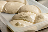 Close-up image of freshly prepared pizza dough balls placed on a tray, showcasing their texture and readiness for baking