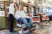 Professioneel barbier verzorgt het haar van een van zijn mannelijke klanten in de barbershop.