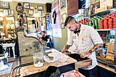 Professional Barber managing the Vintage Cash Register of Schorem Barber Shop, Nieuwe Binnenweg, Rotterdam, Netherlands.