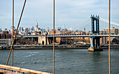 New York City, USA. The Manhattan Bridge and the Skyline of Manhattan from the Brooklyn Bridge Walkway.