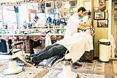 Professioneller Friseur und Haarschneider rasiert seinen Kunden im Schorem Barber Shop am Nieuwe Binnenweg, Rotterdam, Niederlande.