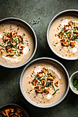 Mushroom soup bowls topped with wild mushrooms on a green surface