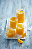 Fresh, cold squeezed orange juice garnished with orange on a blue wooden backround