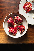 Pomegranate in ceramic bowl on wooden table.