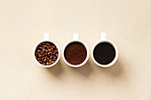 Sequential display of coffee beans, grounds, and brewed coffee in white cups.