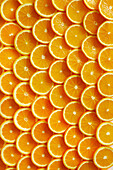 Many freshly cut orange slices laid out like scales from above