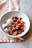 Apple and rhubarb crumble with ice cream in a bowl