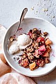 Apple and rhubarb crumble with ice cream in a bowl