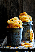 Homemade crispy fried onion rings in a metal cup