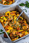 Baked chicken thighs and potatoes in a baking pan photographed from front view.