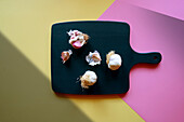 Garlic bulbs on a cutting board with a colour block and geometric shadow aesthetic.