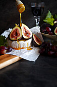 Brie cheese served with figs, honey and grapes, with negative copy space.