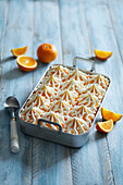 Homemade fresh vanilla orange ice cream dessert with meringue pieces on a blue wooden background