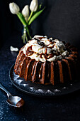 Caramel bundt cake in dark setting with flowers