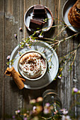 Mexican Hot Chocolate with whipped cream on a dark wood background with flowers, cookies and cinnamon sticks.