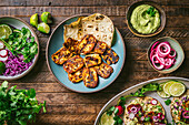 Plate of oan fried Halloumi cheese, with colorful garnishes in bowls and platter of assembled tacos