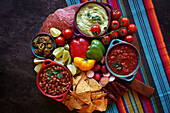 Mexican theme charcuterie board grazing platter with guacamole, salsa, beans, jalapenos, chorizo, and tortilla chips.