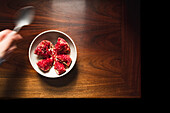 Pomegranate in ceramic bowl on wooden table.