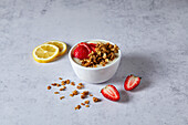 Lemon and strawberry smoothie bowl with granola on a neutral background with soft shadows