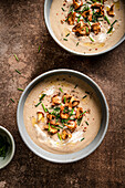 Mushroom soup topped with wild mushrooms on a rustic brown surface