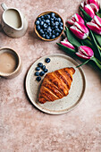 Croissant and blueberries on a ceramic plate