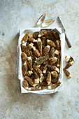 Black morels in a white market box on a beige stone background