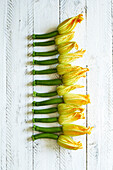 Fresh home-grown zucchini flowers on a white wooden background