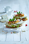 Two slices of baguette topped with blue cheese, chutney, grapes, apples and water cress