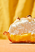 Lemon meringue pie with bright hard light on an orange foreground and yellow backdrop