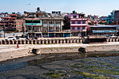 Blick über das verschmutzte Wasser des heiligen Bagmati-Flusses vor typischen nepalesischen Häusern, Pashupatinath, Kathmandu, Nepal, Asien