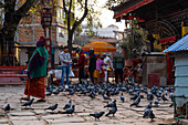 Devotees and prayers in front of a Hindu temple with religious people and pigeons, Kathmandu, Nepal, Asia