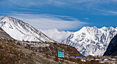 Towering ice capped mountains of Tserko Ri and Gangchempo, and beautiful turquoise mountain lodge in Langtang village, Langtang Valley, Himalayas, Nepal, Asia