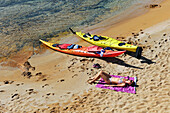 Kajakfahrer ruht sich am Strand einer kleinen Insel in der Bucht Cala Pregonda in der Nähe von Kap Cavalleria an der Nordküste von Menorca, Balearen, Spanien, Mittelmeer, Europa aus