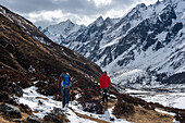 Two hikers in high altitude winter valley on the Langtang trek in Kyanjin Gompa, Himalayas, Nepal, Asia