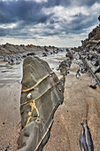 A rocky shore at low tide and under grey skies; at Welcombe Mouth, Hartland, north Devon, England, United Kingdom, Europe