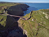 Eine Luftaufnahme der dramatischen Ruinen von Tintagel Castle, angeblich der Geburtsort von König Artus, auf einer felsigen Insel vor der Küste, in der Nähe der Stadt Tintagel, Cornwall, England, Vereinigtes Königreich, Europa