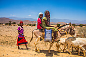 Kinder reiten auf einem Esel zu einem Wasserloch im Tiefland von Eritrea, Afrika