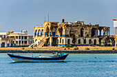 Fischerboot schwimmt vor dem zerbombten Regierungspalast in der Altstadt von Massawa, Eritrea, Afrika