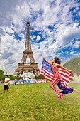 Patriotic American Woman jumping and cheering for Team USA and the Paris 2024 Olympics in front of the Eiffel Tower, Paris, France, Europe