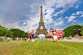 Patriotische amerikanische Frau springt und jubelt für das Team USA und die Olympischen Spiele Paris 2024 vor dem Eiffelturm, Paris, Frankreich, Europa