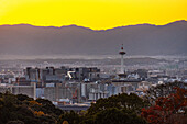 Skyline von Kyoto bei Sonnenuntergang mit leuchtend orangefarbenem Himmel, Kyoto Tower, Kyoto, Honshu, Japan, Asien