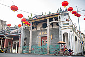 A trishaw driver resting on the side of the street of George Town, Penang, Malaysia, Southeast Asia, Asia