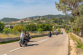 Blick auf Motorradfahrer und die auf einem Hügel gelegene Stadt Selva, Mallorca, Balearen, Spanien, Mittelmeer, Europa