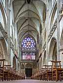 Innenansicht der Eglise Saint Pierre mit gotischer Architektur, Reihen von Holzstühlen und beeindruckenden Buntglasfenstern in Caen, Normandie, Frankreich.