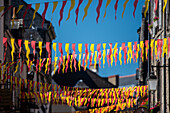 Vibrant red and yellow flags hanging across a charming street in Guerande, France on a sunny day.