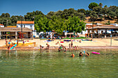 Familien und Kinder genießen einen sonnigen Tag am Flussstrand in San Nicolas del Puerto, Sevilla, Spanien.