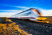 A high-speed train blurs by on the tracks through the countryside near Carrion de los Cespedes in the province of Sevilla, Andalusia, Spain.