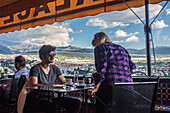 Two people enjoying coffee on a terrace with a panoramic view of Granada, Andalusia, Spain. The beautiful landscape and relaxed atmosphere create a serene environment.