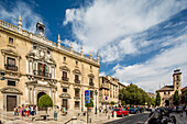 Schöner Blick auf das Edificio de la Audiencia an der Plaza Nueva, Granada, Spanien, unter einem klaren blauen Himmel mit Besuchern.