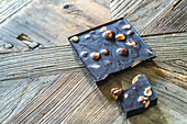 Homemade chocolate with almonds, broken into pieces, resting on a rustic wooden surface.